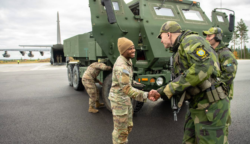 Svenske styrker tar imot amerikanske styrker ved Vidselbasen mens artillerisystemet HIMARS lastes av transportflyet Hercules. (Foto: Hampus Hagstedt/Försvarsmakten)